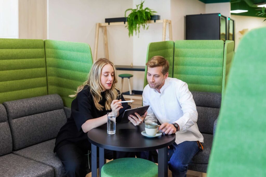 What is a collaboration hub? a man and woman sitting at a table with green chairs