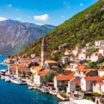 Scenic coastal village with mountains backdrop.
