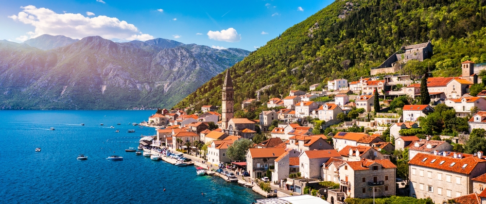Scenic coastal village with mountains backdrop.