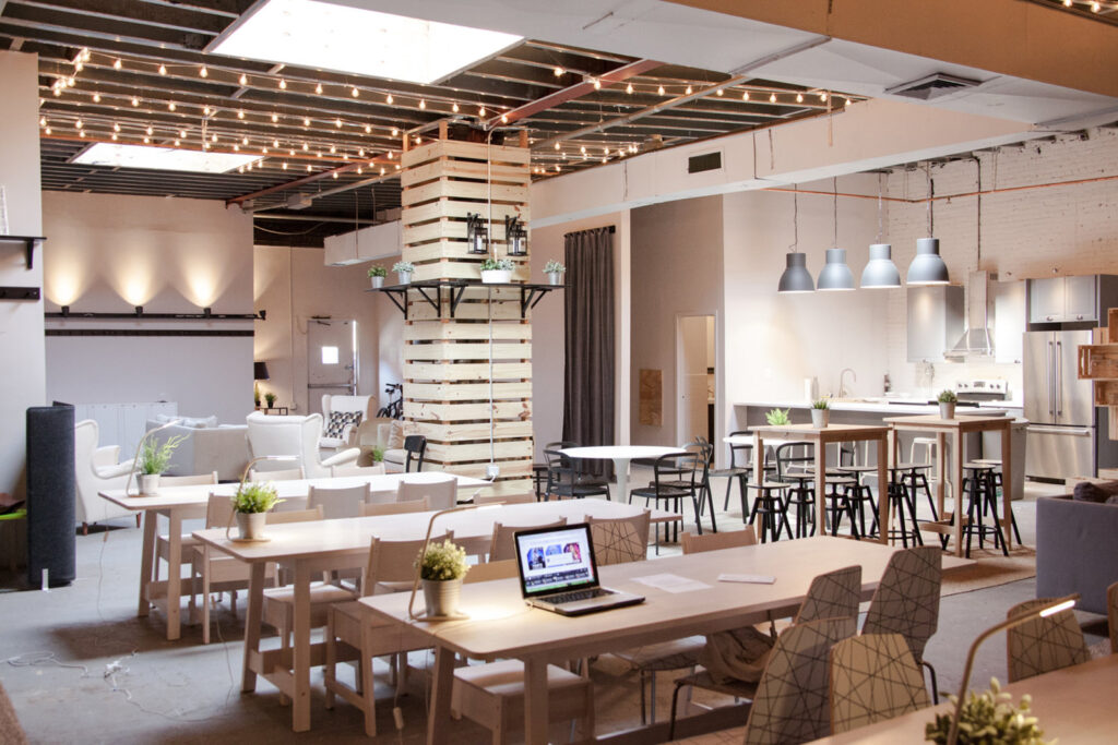 a room with tables and chairs and a laptop