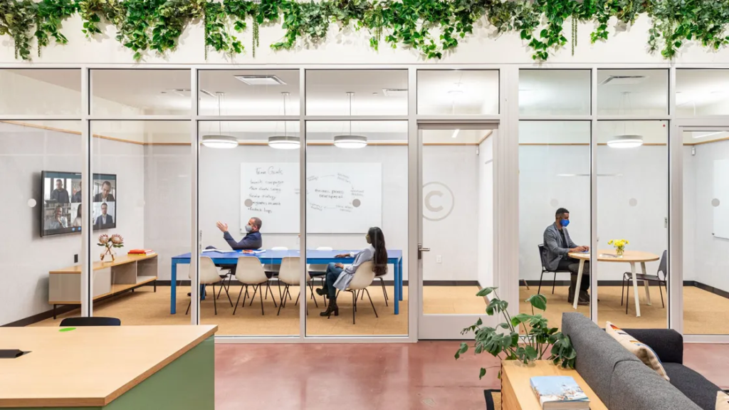a group of people sitting at a table in a room with glass walls