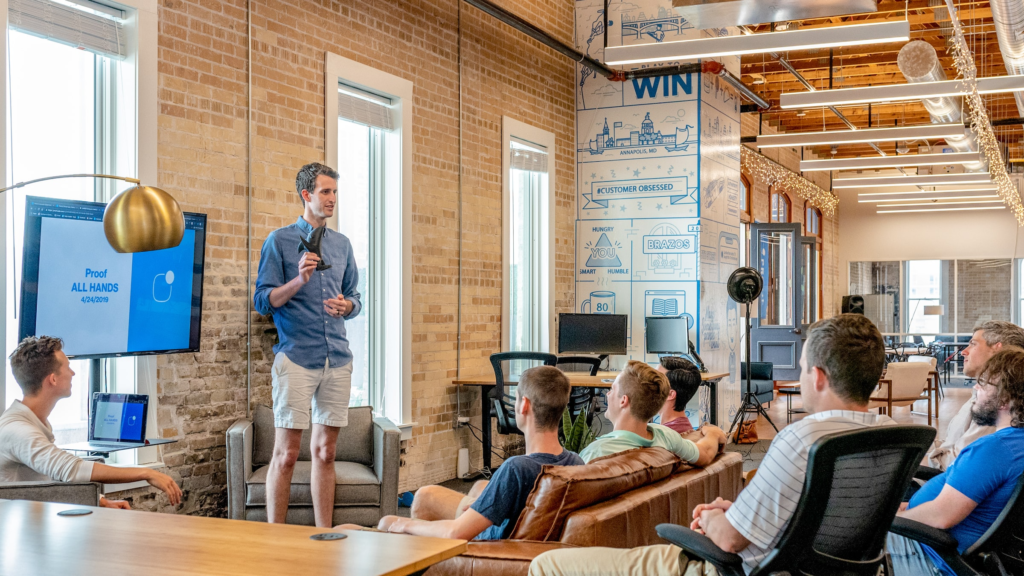 Nine benefits of coworking spaces a man standing in front of a group of people sitting on couches