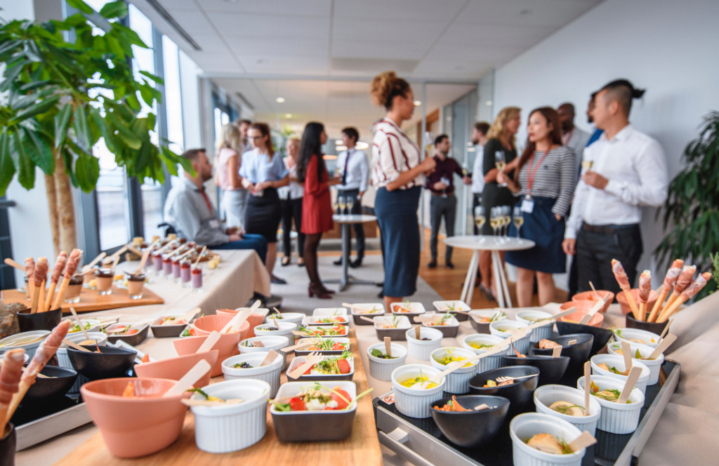 a group of people standing around a table full of food