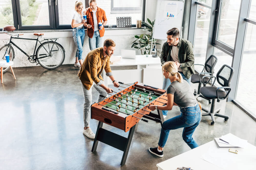 Nine benefits of coworking spaces a group of people playing foosball