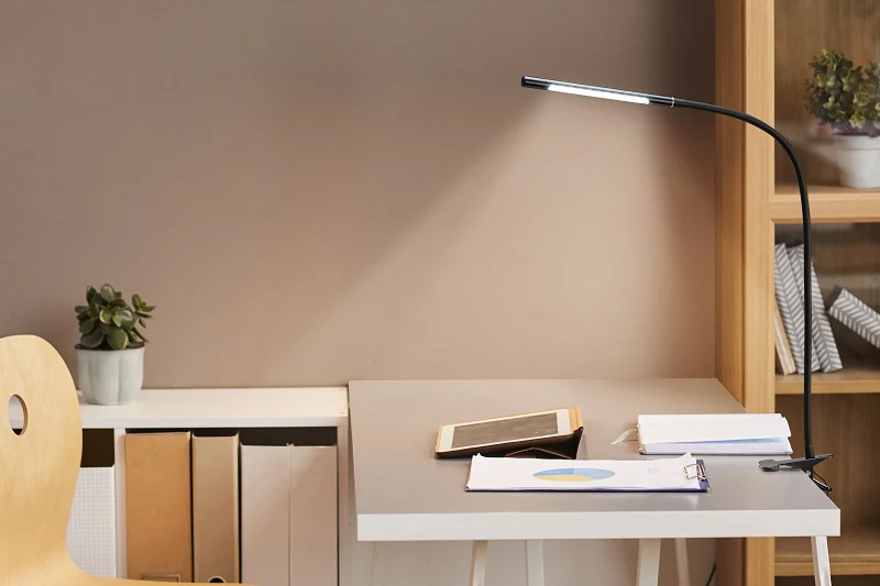 a desk with a lamp and a tablet on it