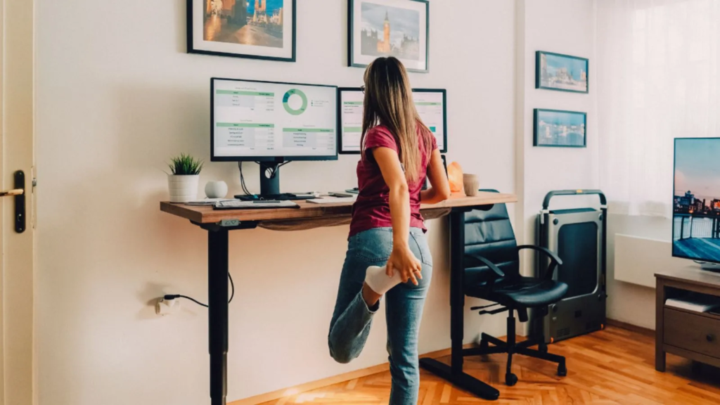a woman stretching her leg in front of a computer
