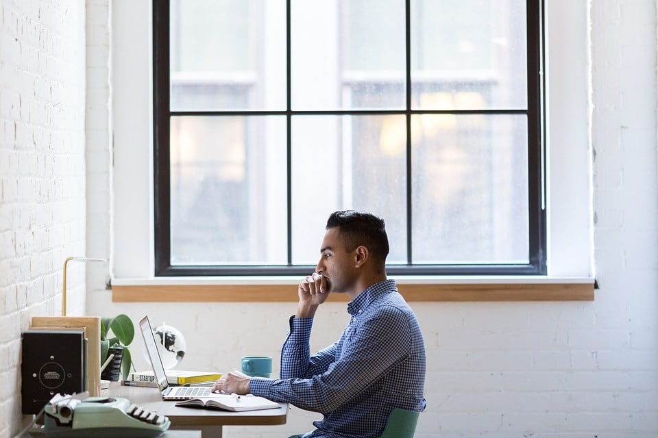 a man sitting at a desk with a laptop