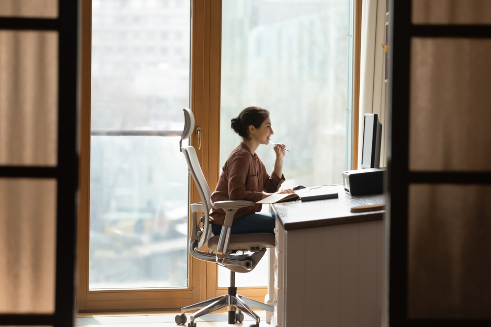Five ways to set up your desk for productivity Woman working at a desk, thoughtful.