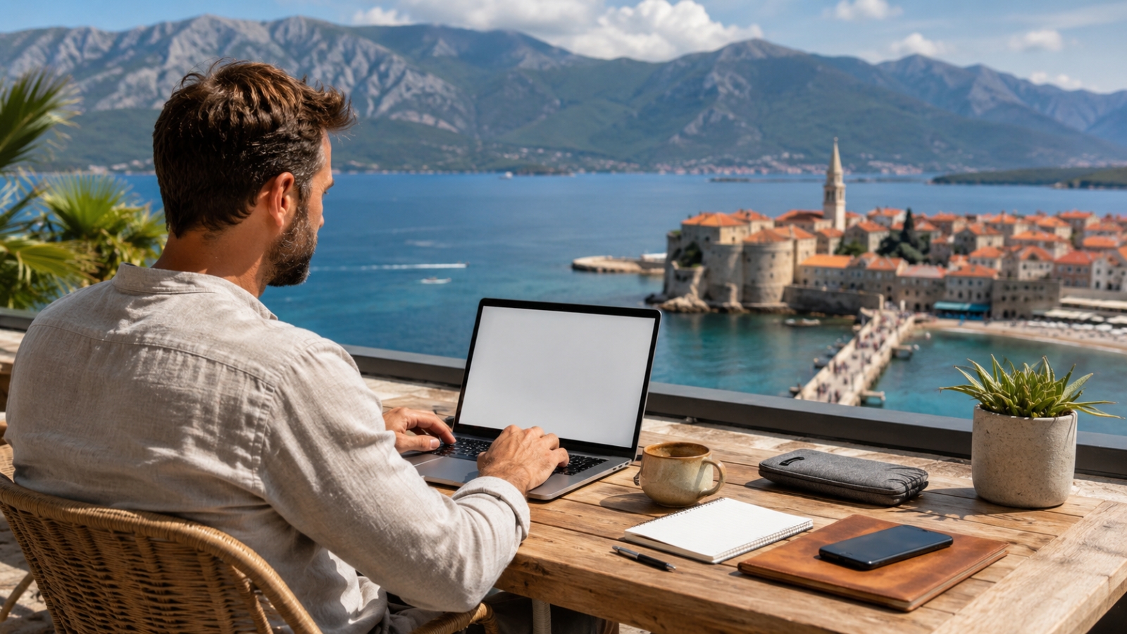 Remote worker using a laptop on a terrace overlooking the Adriatic coast in Budva, Montenegro